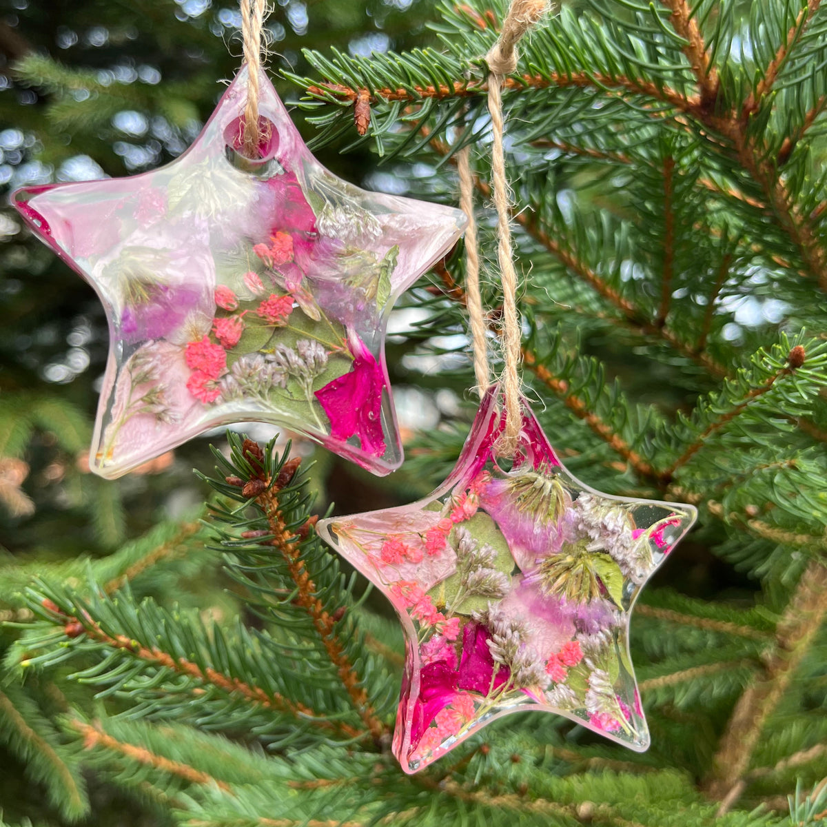 Decorative star-shaped ornaments with floral design hanging on a Christmas tree.